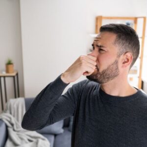 Man covering his nose to not smell his balls