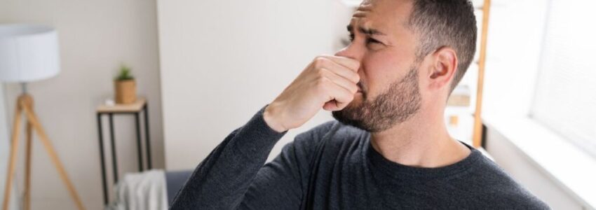 Man covering his nose to not smell his balls
