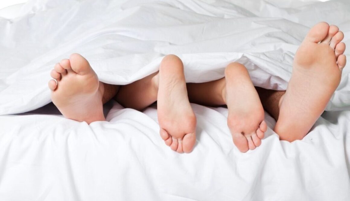 A couple under the sheets with their feet visible.